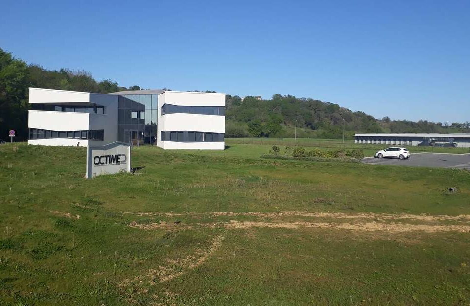 bureau-moderne-et-enseigne-octime-devant-une-pelouse-verte